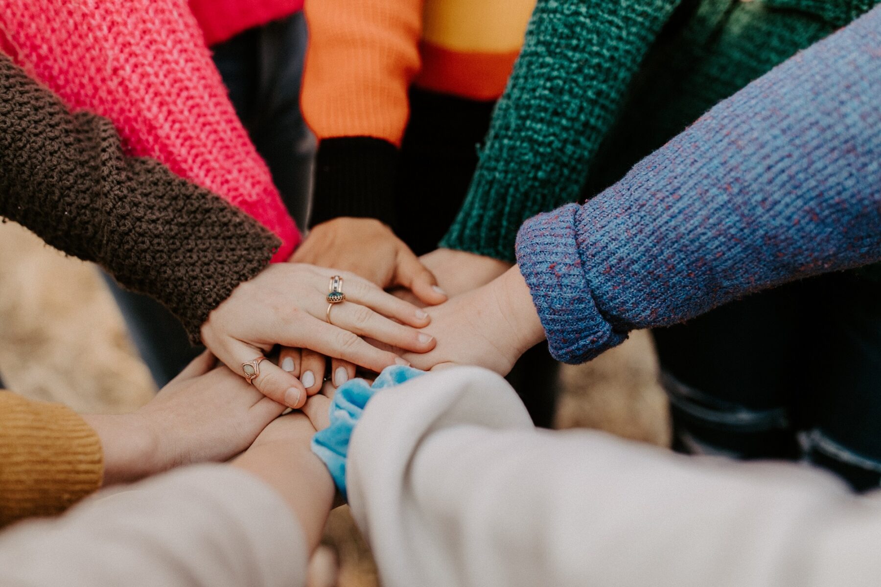 diverse group with 1 hand on top of each other stacked