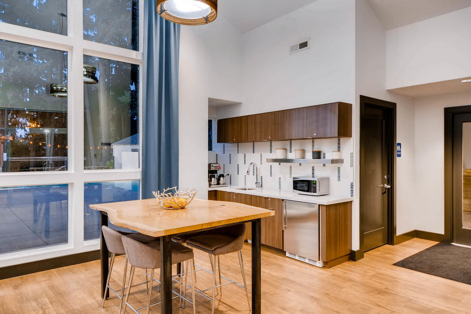 Community kitchen space with view of sink, microwave, and seating for 4 at a wooden square table