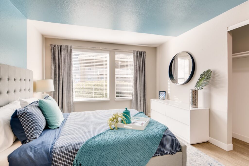 staged bedroom with large windows and blue accent wall