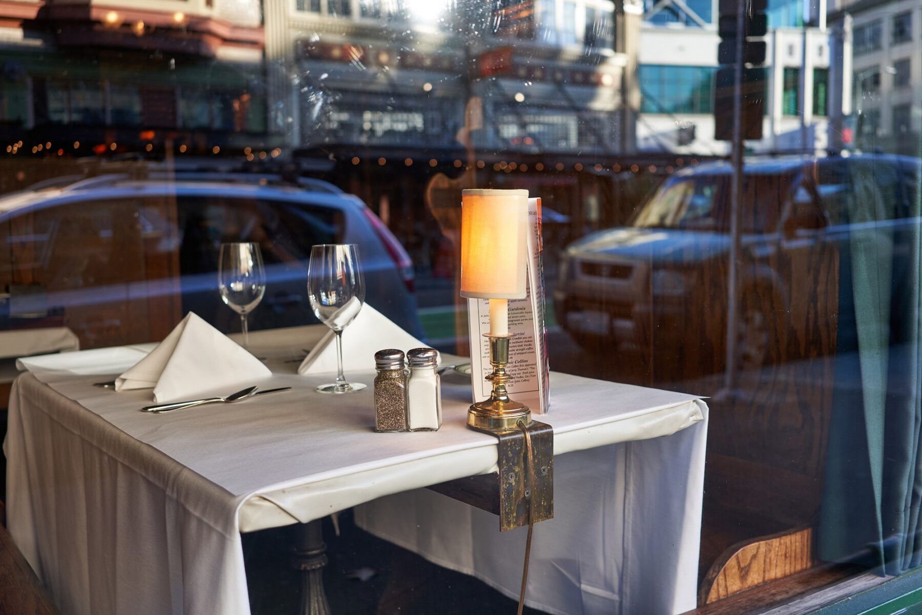 square table with white table cloth and salt and pepper and two wine glasses outside a Restaurant