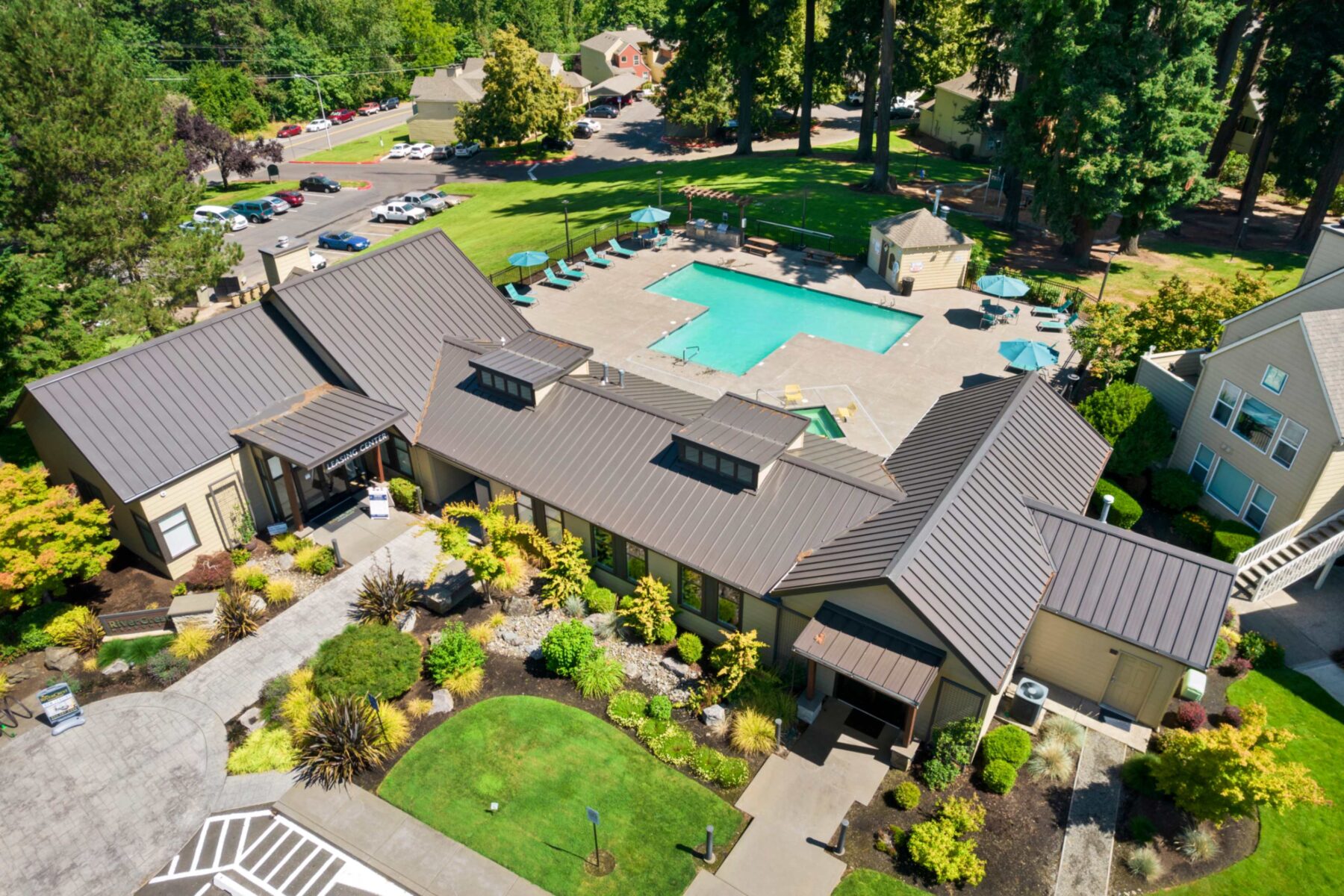 Aerial view of Pool with deck chairs, tables with umbrellas, and large trees