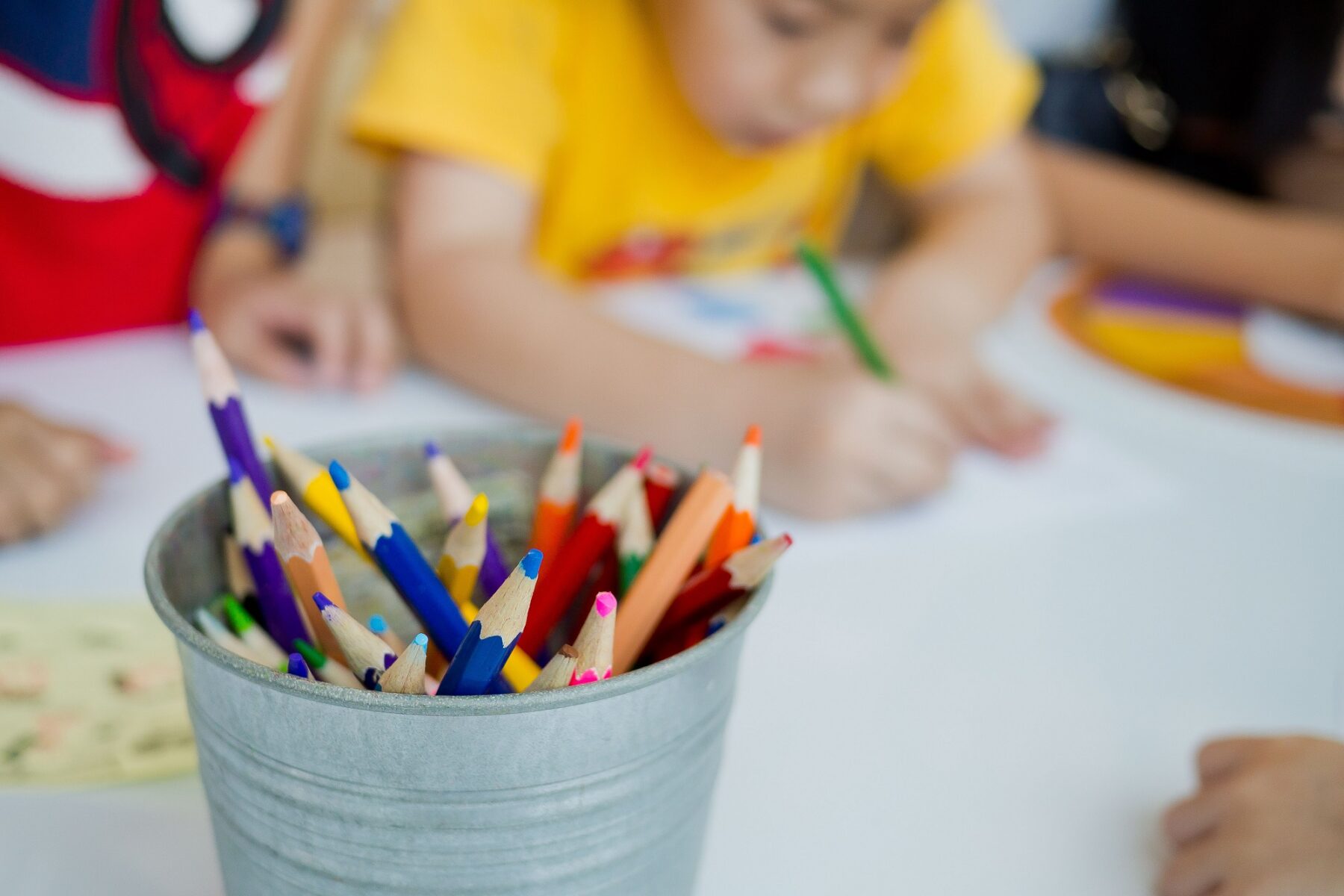 Kids using colored pencils to draw at a desk