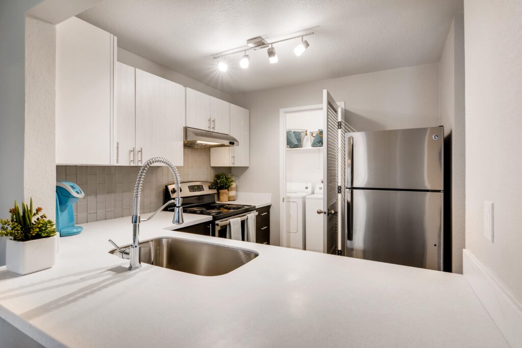Kitchen with white counters, stainless steel appliances, and washer dryer closet