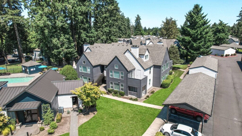 aerial view of two story apartments, clubhouse, and covered parking spots