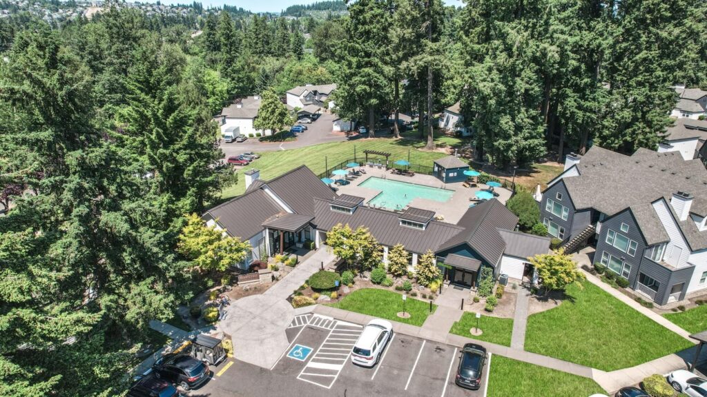 aerial view of clubhouse with pool and patio, nearby apartments and parking lot
